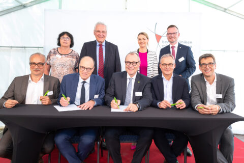 Im Rahmen der Grundsteinlegung des Bauabschnitts Eins der Generalausbauplanung des Klinikums am Europakanal in Erlangen unterzeichneten Dr. Albrecht Bender, Kaufmännischer Direktor Uniklinikum Erlangen, Prof. Dr. Dr. h. c. Heinrich Iro, Ärztlicher Direktor Uniklinikum Erlangen, Dr. Matthias Keilen, Vorstand Bezirkskliniken Mittelfranken, Prof. Dr. Arnd Dörfler, Direktor Neuroradiologisches Institut Uniklinikum Erlangen, und Prof. Dr. Michael Uder, Direktor Radiologisches Institut Uniklinikum Erlangen (vordere Reihe, v. l. n. r.), im Beisein von Dr. Ute Salzner, Bezirksrätin, Joachim Herrmann, Bayerischer Staatsminister des Innern, für Sport und Integration, Judith Gerlach, Bayerische Staatsministerin für Gesundheit, Pflege und Prävention, und Peter Daniel Forster, Bezirkstagspräsident des Bezirks Mittelfranken und Verwaltungsratsvorsitzender der Bezirkskliniken Mittelfranken (hintere Reihe, v. l. n. r.), den Kooperationsvertrag. Foto: Knut Pflaumer