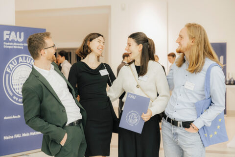 2 männliche und 2 weibliche Studierende stehen beisammen und lachen sich kaputt.