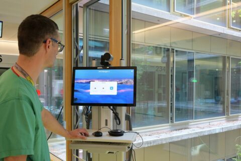 Arzt im grünen Kittel schaut auf Monitor.