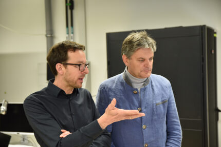 Professor Nicolas Vogel und FAU-Präsident Joachim Hornegger reden und schauen sich etwas gemeinsam an.