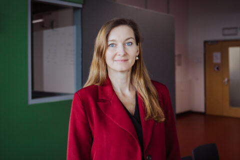 Porträt von Dr. Maria Hammer, eine frau mit langem blondem Haar und roter Jacke.